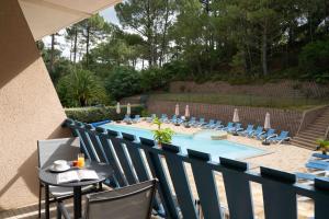 a blue fence with a table and chairs next to a pool at Hotel Logis Lacotel in Hossegor