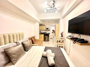 sala de estar con cama y TV grande en City Nest Makati with Rooftop pool and Free Netflix, en Manila