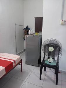 a room with a chair and a refrigerator at Bilik Transit Nilai in Nilai