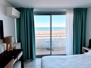 um quarto de hotel com uma cama e vista para a praia em Brasilia Hôtel em Palavas-les-Flots