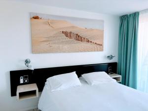 - une chambre avec un lit et une photo de désert dans l'établissement Brasilia Hôtel, à Palavas-les-Flots