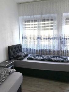 een bed in een kamer met een raam met gordijnen bij Unterkunft Mara in Oberhausen