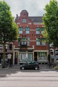 um carro preto estacionado em frente a um edifício de tijolos em De Jonker Urban Studios & Suites em Amsterdã