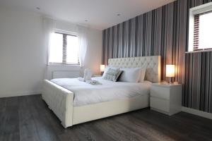 a white bedroom with a large white bed with two lamps at Swanwick House in Broughton