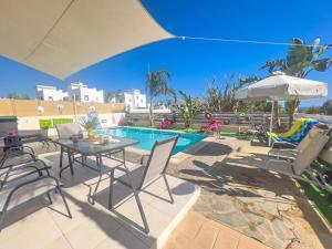eine Terrasse mit Tisch und Stühlen und einem Pool in der Unterkunft Villa Anna Maria, Kapparis in Paralimni