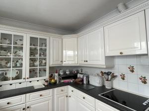 a kitchen with white cabinets and black counter tops at Curlews in Feock