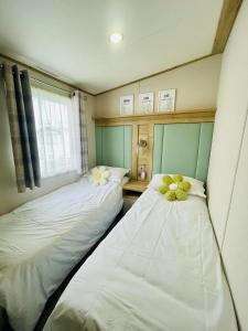 two twin beds in a room with a window at Pure-Living West Sands Sunshine and Sea View - 3 Bedroom lodge at SEAL BAY in Selsey
