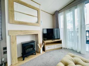 a living room with a fireplace and a television at Pure-Living West Sands Sunshine and Sea View - 3 Bedroom lodge at SEAL BAY in Selsey