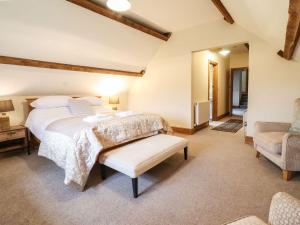 a bedroom with a large bed and a chair at The Barn in Corwen