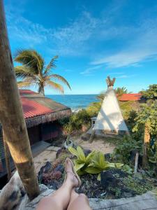 a person with their feet up on a beach with a teepee at Pousada Paraíso das Tartarugas in Pipa