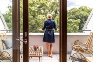 una donna in piedi su un balcone che guarda fuori dalla finestra di Resort Lednice - Eisgrub a Lednice