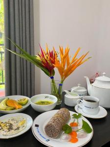 a table with plates of food and a vase with flowers at Olive Launch in Weligama