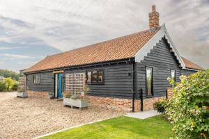 een klein zwart huisje met een bakstenen buitenkant bij Large immaculate rural conversion - The Milking Parlour in Ipswich