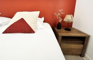 a bedroom with a white bed with a red wall at Le Patio - Vallée d'Aspe in Bedous