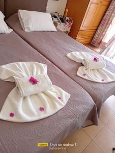 twee handdoeken op een bed met roze bloemen erop bij Villa Filia in Almiros strand
