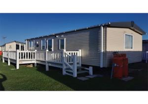 a mobile home with a deck and a fire hydrant at Caravan on Fantastic site in Dunbar