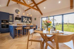 a kitchen and dining room with a wooden table and chairs at Large immaculate rural conversion - The Milking Parlour in Ipswich
