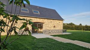 a stone building with a glass door in a yard at Meublé 5* Au gré des saisons in La Baconnière
