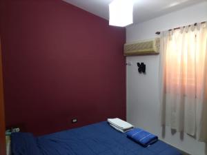ein Schlafzimmer mit einem blauen Bett und einer roten Wand in der Unterkunft Casa Norte in La Rioja