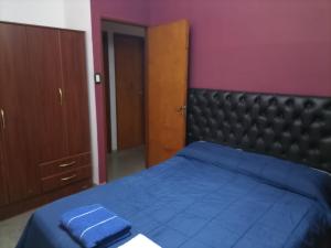 Schlafzimmer mit einem blauen Bett und einem schwarzen Kopfteil in der Unterkunft Casa Norte in La Rioja