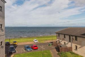 a group of cars parked in a parking lot next to the ocean at Coastal Apartment 2 Bedrooms, Sleeps upto 6, Free Parking in Prestonpans