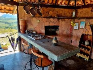 a kitchen with a counter with a stove and a fireplace at Recanto das Mels no Alto da Chapada in Alto Paraíso de Goiás