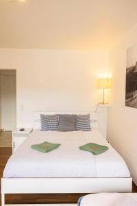 ein weißes Bett mit zwei grünen Kissen darauf in der Unterkunft Studio Lux city in Luxemburg (Stadt)