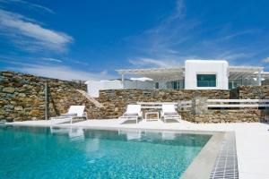 una piscina con due sedie e una casa di Luxury Mykonos Villa - 4 Bedrooms - Sea View & Private Pool - Elia a Elia Beach