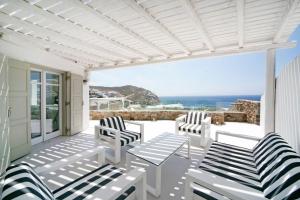 埃利亞海灘的住宿－Luxury Mykonos Villa - 4 Bedrooms - Sea View & Private Pool - Elia，一个带白色椅子的海景庭院