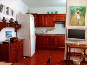 a kitchen with a white refrigerator and a tv at Casa Perla - Cerca de la playa in Playa de Santiago