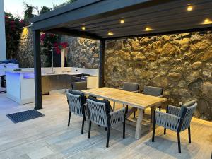 a patio with a wooden table and chairs and a stone wall at Villa Aylinda with private heated Pool in Bodrum City