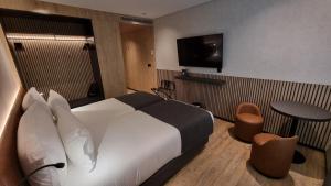 Habitación de hotel con cama, mesa y TV. en Hotel Principe Avila en Lisboa