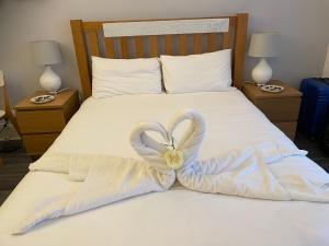 a bed with two towels in the shape of a heart at Bournemouth Hot Tub & Sauna Holiday Let in Bournemouth