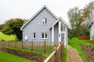 a blue house with a wooden fence in a yard at Trewhiddle Retreat V17 by Together Travel - Luxury 4-Bedroom Villa in St Austell