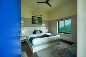um quarto com uma cama, uma ventoinha de tecto e uma janela em Shalom Backpackers Rishikesh em Rishikesh