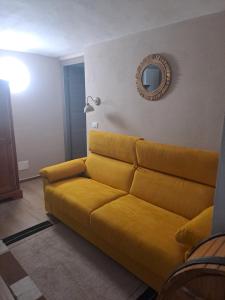 een gele bank in een woonkamer met een spiegel bij La coccinella in Oulx