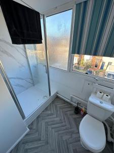 a bathroom with a toilet and a shower and a window at Entire 3 Bedroom Apartment in Felixstowe in Felixstowe