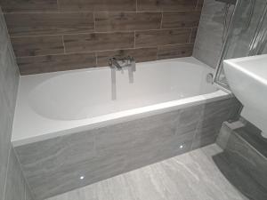 a bathroom with a shower with a sink and a bath tub at Bournemouth Hot Tub & Sauna Holiday Let in Bournemouth
