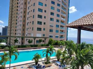 ein Schwimmbad vor einem hohen Gebäude in der Unterkunft Habitacion privada en apartamento compartido in Santo Domingo