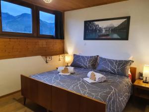 a bedroom with a bed with two lamps and windows at La Finestra sui Monti - Alpine Stay Apartments in Cavalese