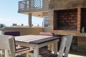 a wooden table and chairs on a patio with a fireplace at Dolphin View 20 @ LongBeach in Langstrand