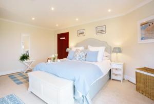 a bedroom with a large white bed with blue pillows at Home near Port Isaac sleeps 10 in Port Isaac