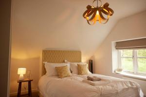 1 dormitorio con 1 cama blanca grande con lámpara de araña en Vine Cottage, en Shepton Mallet