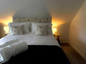 a bedroom with a bed with white sheets and pillows at Vine Cottage in Shepton Mallet