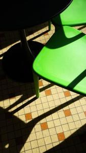 a green chair sitting on top of a tiled floor at Saint Michel - Centre Ville - Espace Coty in Le Havre
