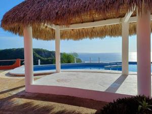 een resort met een zwembad en een rieten parasol bij Bungalow Maya Luna in Playa Estacahuite