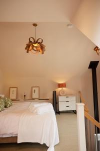 um quarto com uma cama branca e um lustre em The Old Winery Cottage No1 em Shepton Mallet