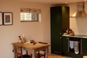 cocina con mesa y armario verde en The Old Winery Cottage No1, en Shepton Mallet