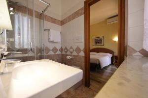 een badkamer met een wastafel, een douche en een bed bij Hotel Primavera in Peschiera del Garda