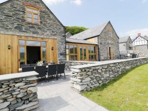 a stone house with a patio and a stone wall at Hay Store in Corwen